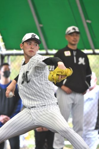 ブルペンで投げ込む佐々木朗希。奥は吉井監督＝２０２３年２月、沖縄県石垣市