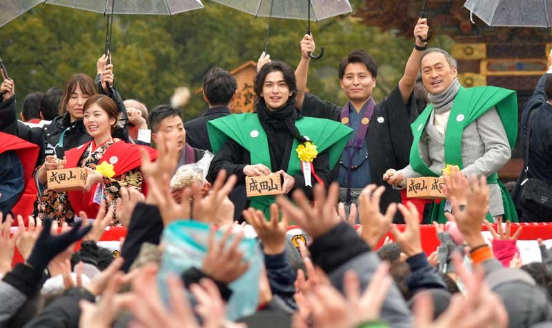 成田山新勝寺の節分会で特設舞台から参拝客に豆をまく大河ドラマ出演者の（左から）小芝さん、横浜さん、渡辺さん＝２日、成田市