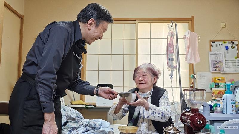 北見さん（左）にコーヒーをいれてもらい、笑顔で乾杯する下平さん＝２月２７日午後、佐倉市
