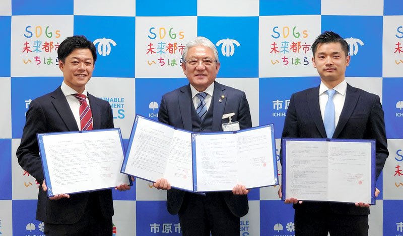 協定書を手にする川口ＣＥＯ（左）と河田社長（右）。中央は小出譲治市長＝市原市役所