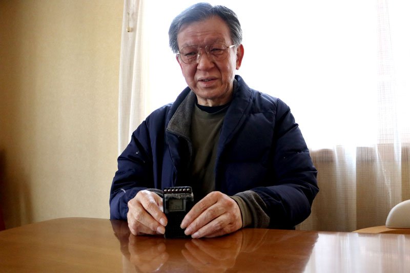 お気に入りのポータブルラジオを手に持つ塚原さん＝３月、松戸市の自宅で