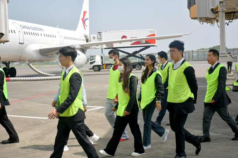 旅客機に機内食が搭載される駐機場を歩く見学会参加者＝２０日、成田市
