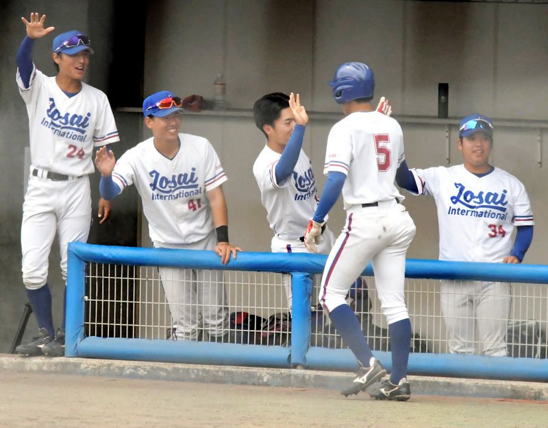 城国大－千経大２回戦　６回裏城国大２死二塁、田中陽の適時打で生還した幸鉢（５）を笑顔で迎える選手ら＝１９日、長生の森