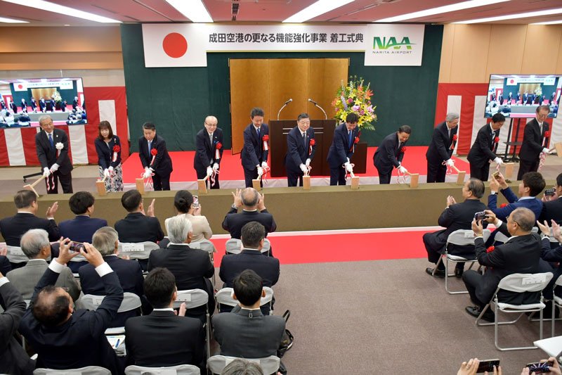 成田空港のＣ滑走路新設とＢ滑走路延伸を行う機能強化の本格工事開始を記念した着工式典でくわ入れする関係者＝２５日、成田市のＮＡＡ本社