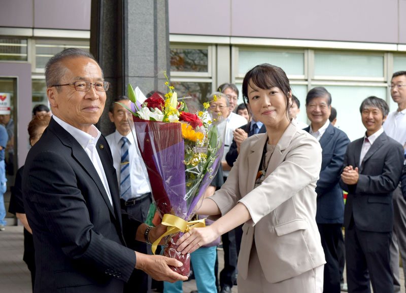 市職員（右）から花束を贈られる松戸市長＝２４日、船橋市役所