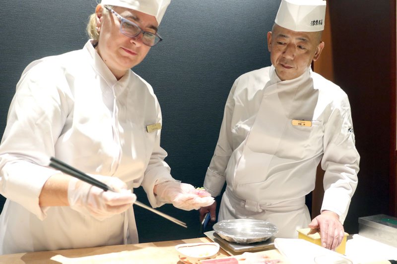 浅間料理長（右）の手ほどきを受けて、寿司作りの修行をするラリーサさん＝８月、千葉市中央区の波奈本店