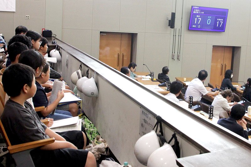 学校名を定める条例改正案が全会一致で可決された瞬間を傍聴する児童ら＝２６日、館山市議会