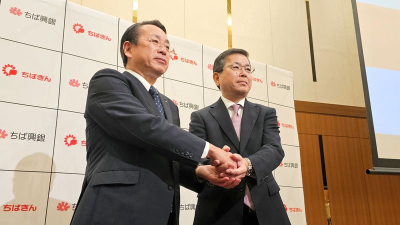 記者会見後に握手する千葉銀の米本頭取（左）と千葉興銀の梅田頭取＝２９日、千葉市中央区