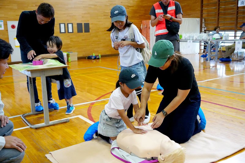人形で心臓マッサージを体験する親子＝５日、旭市立干潟小体育館
