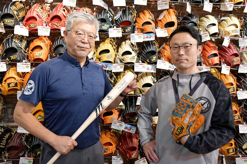 壁をグラブが埋め尽くす「超野球専門店ＣＶ」での中村俊也会長（左）と勇太社長＝鎌ケ谷市