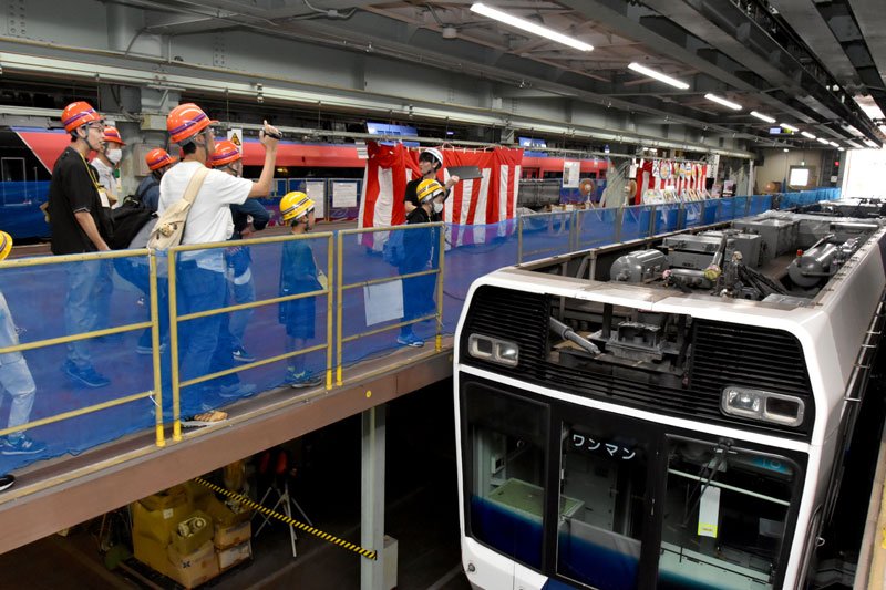 車両屋根上の制御回路やブレーキなどの説明を聞く来場者＝千葉市稲毛区