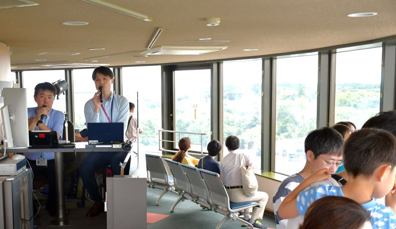 成田空港の離着陸機を見ながら、どのような指示が管制塔からパイロットに出ているか実況する管制官（左２人）＝芝山町の航空科学博物館