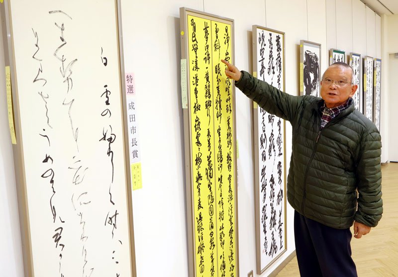 成田市書道協会展の受賞作品について解説する飛田会長＝同市