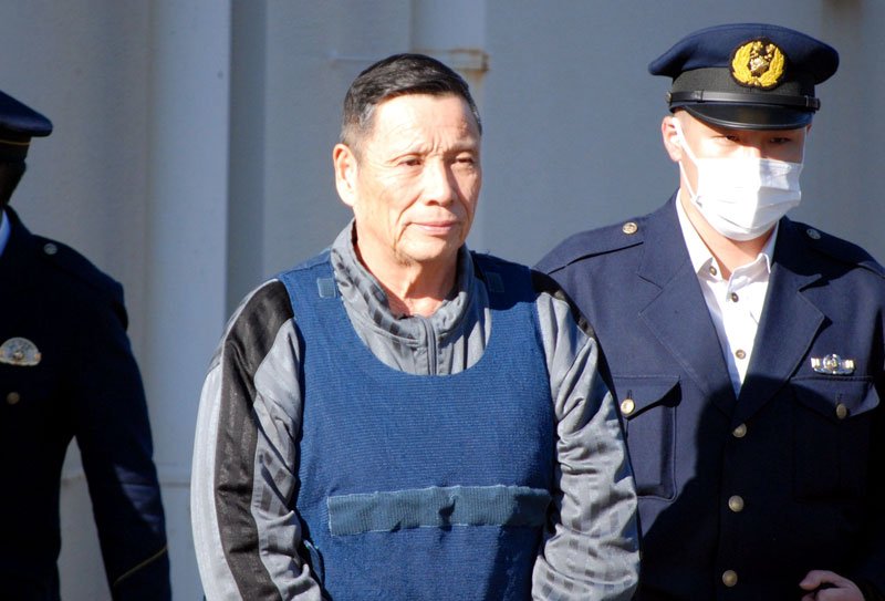 移送のため警察署を出る小川容疑者（中央）＝７日午前９時半ごろ、千葉市内