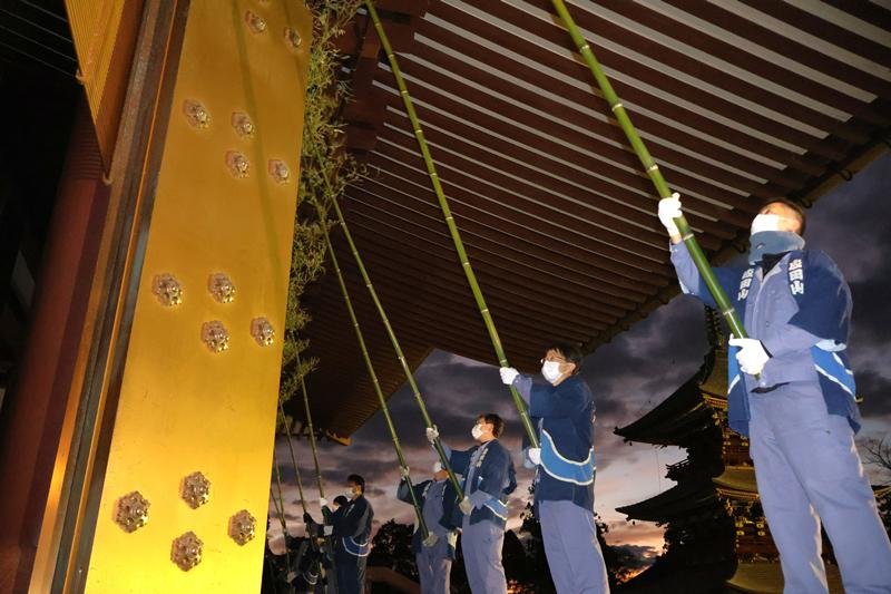 日の出でが近づき空が明るくなり始める中、成田山新勝寺の大本堂をササ竹で清める職員＝１３日午前６時５分ごろ、成田市