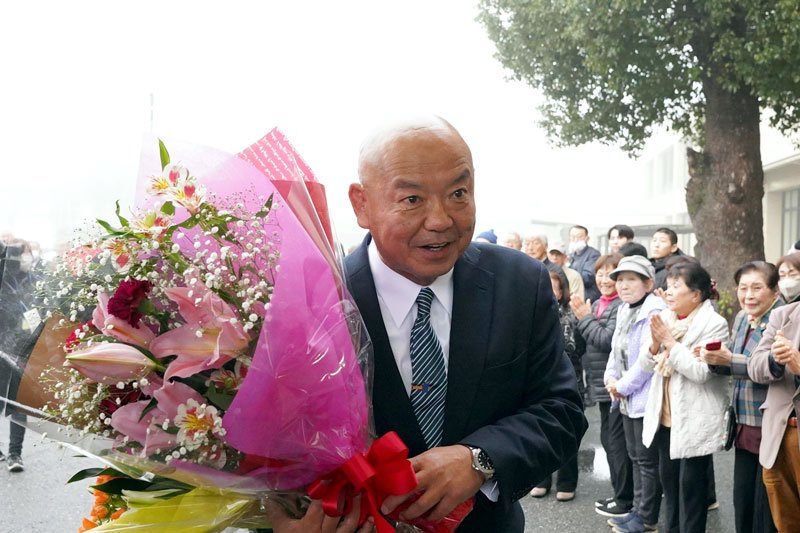 市民や職員から初登庁の出迎えを受けて笑顔を見せる小路市長＝２５日、いすみ市役所