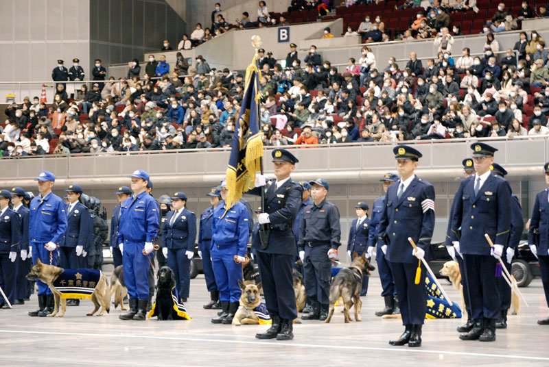 観覧客を背に青山県警本部長の訓示を受ける警察官と警察犬＝１３日、千葉市美浜区の幕張メッセ