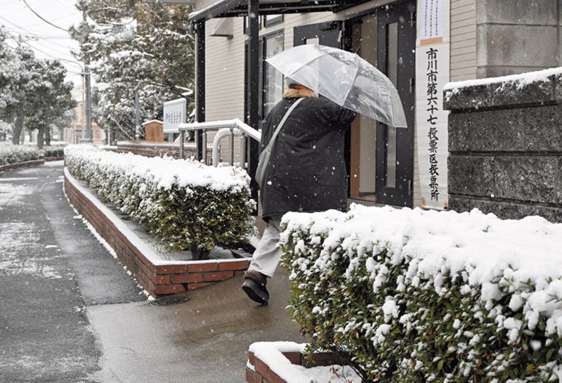 衆院選の投開票日の８日、県内は広範囲で雪が積もり、大雪警報も出た。朝から雪が降りしきる中、投票所へ足を運ぶ有権者も＝市川市
