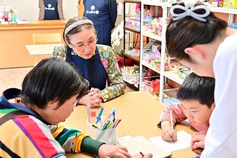 手紙を書く子どもを見守る店長の吉田さん（奥）＝１日、千葉市中央区
