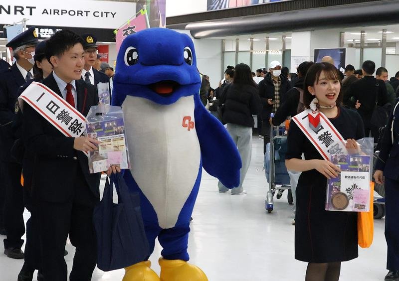 成田空港から入国した外国人旅客らに交通安全を呼びかける一日署長の地上係員ら＝８日、成田市
