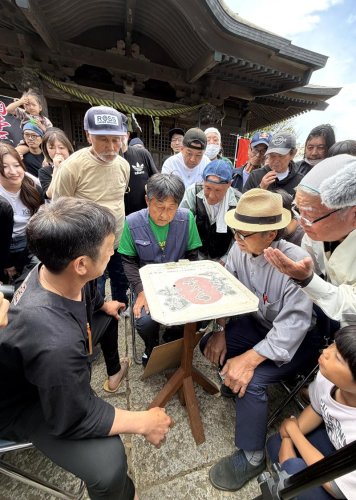 小さな土俵上で繰り広げられるクモの戦いに熱い視線を送る人たち＝４日、富津市
