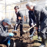 ブドウの苗木を植える原科学長（右）ら。畑の上には発電用の太陽光パネルが設置された＝５日、市川市の千葉商科大学
