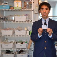 自室にある実験道具の横で、危険物取扱者免状を手にする小早志さん