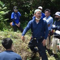 沖ノ島の現状やタブノキの植え方を説明する高田さん
