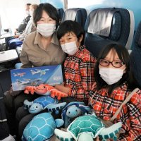 フライングホヌの機内でぬいぐるみ３種類と抽選で当たったモデル機を持って喜ぶ吉澤さん親子＝５月２１日