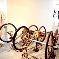 自転車の空間展示を説明する上野さん（左）。触っている１台は家からペダルをこいで搬入したという