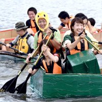 笑顔で段ボール船をこぎ進める参加者