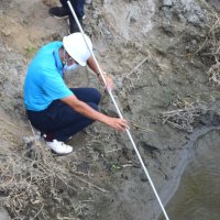 川底から吹き出る天然ガスを集め火を付ける実行委メンバー＝睦沢町
