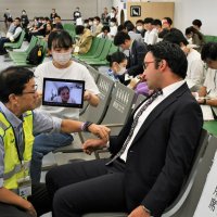 タブレットを介して通訳を受けながらけが人を診察する訓練を行う医師（左）
