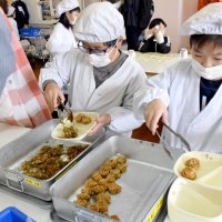 給食の準備でホタテフライを盛り付ける児童
