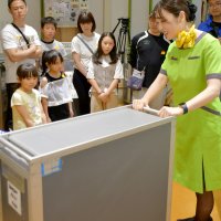 旅客機内で飲食を提供するカートの使い方を客室乗務員（右）から学ぶ子どもたち