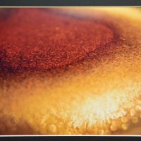 さびたドラム缶のふたに水がたまり、朝日で光っている様子を撮影した作品
