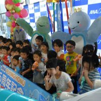 成田空港とハワイを結ぶ「フライングホヌ」初号機の就航５周年を着ぐるみとともに祝う園児たち＝２４日、成田市