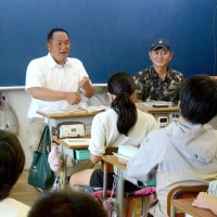 地元九十九里の漁業について児童に説明する尾高さん（左）