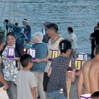 舟に灯籠を渡していく参加者ら＝１４日夕、勝浦市