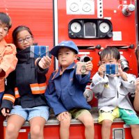 防火衣や救助服を着て完成した小銭入れを見せる子どもたち