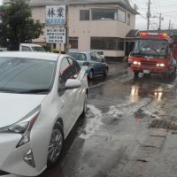 昨年の台風１３号に伴う豪雨で水没し、立ち往生した車（左手前）と、漏れたガソリンを薬剤で処理する消防関係者ら（右奥）＝昨年９月８日、大網白里市駒込
