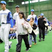 地元の子どもたちと手をつないで入場する選手ら＝１９日、鎌ケ谷市のファイターズ鎌ケ谷スタジアム
