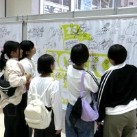 好みのアーティストのサインを見つけて盛り上がる若者ら