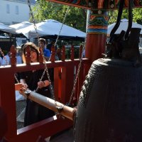 改修が終わった鐘楼で慰霊の鐘をつく参列者ら
