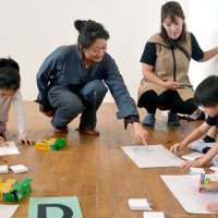 絵を交換しながら描く子どもたちにアドバイスする江上さん（左から２人目）＝１日、市原市の旧白鳥小