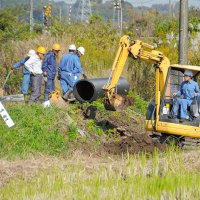 小湊鉄道線路脇ののり面崩落現場で、復旧に向け、埋設されていた用水管の入れ替えを行う作業員＝７日午前１０時ごろ、市原市磯ケ谷