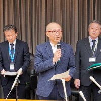 記者団の取材に応じる座長の釜井俊孝・京大名誉教授（中央）＝１８日、県庁