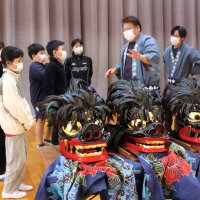 真亀神子舞保存会の会員から獅子の頭について説明を受ける児童＝九十九里町
