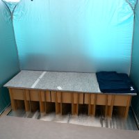 パーティション内の設備の一例として段ボールベッドや毛布が用意された