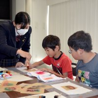 佐倉東高校生（左）のアドバイスを受けながら真剣な表情で友禅染に挑戦する小学生＝佐倉市の夢咲くら館